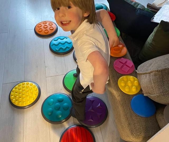 Child stepping across colourful sensory discs during an OTKids therapy session